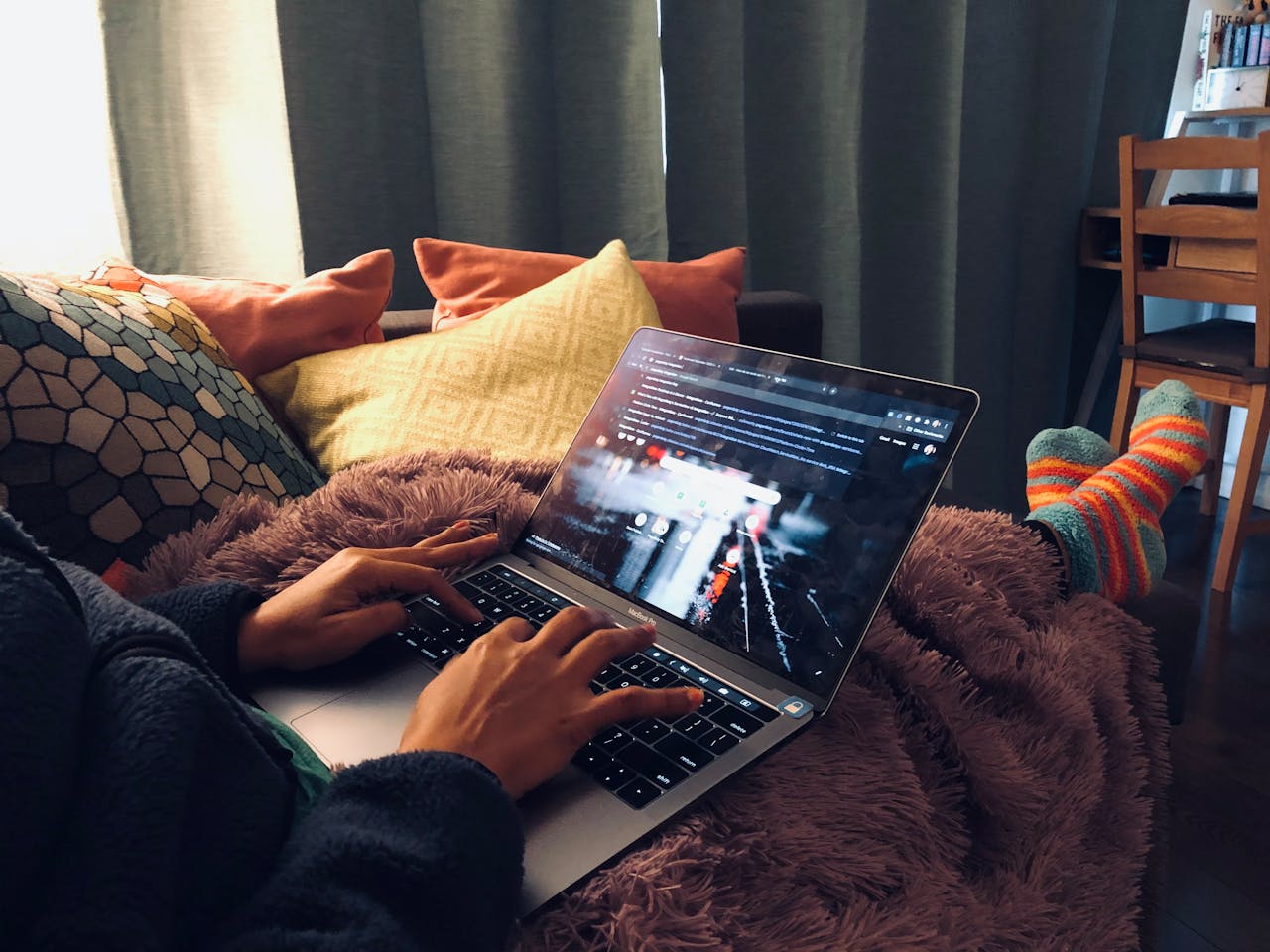The Art of Drawing Readers In: Your attractive post title goes here A person relaxing at home using a laptop on a cozy couch with soft lighting.