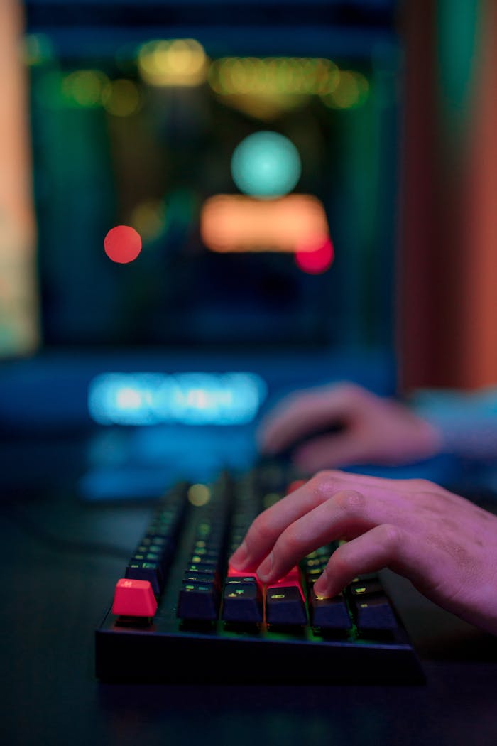 Close-up of hands typing on RGB-lit gaming keyboard with a colorful bokeh background.